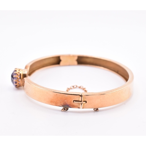 5 - A 15ct gold and amethyst bangle. The 15ct gold bangle set with a single claw mounted round cut ameth... 