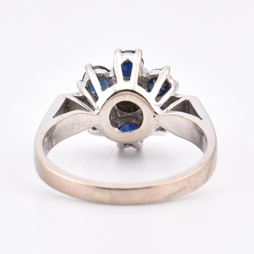 78 - An 18ct white gold sapphire and diamond cluster ring. The ring set with a central diamond framed by ... 