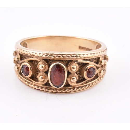 87 - A hallmarked 9ct gold and garnet ring. The ring in the Etruscan style set with three garnets with fi... 