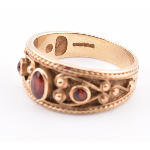 87 - A hallmarked 9ct gold and garnet ring. The ring in the Etruscan style set with three garnets with fi... 