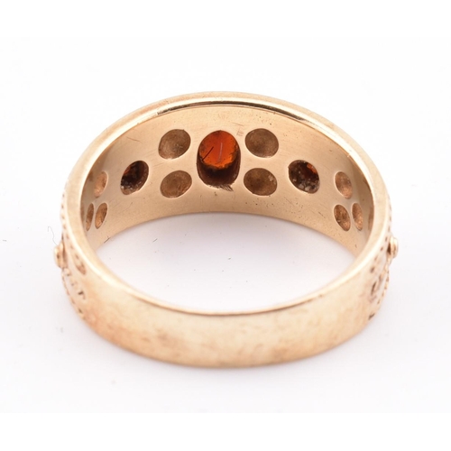 87 - A hallmarked 9ct gold and garnet ring. The ring in the Etruscan style set with three garnets with fi... 