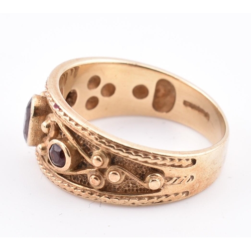 87 - A hallmarked 9ct gold and garnet ring. The ring in the Etruscan style set with three garnets with fi... 