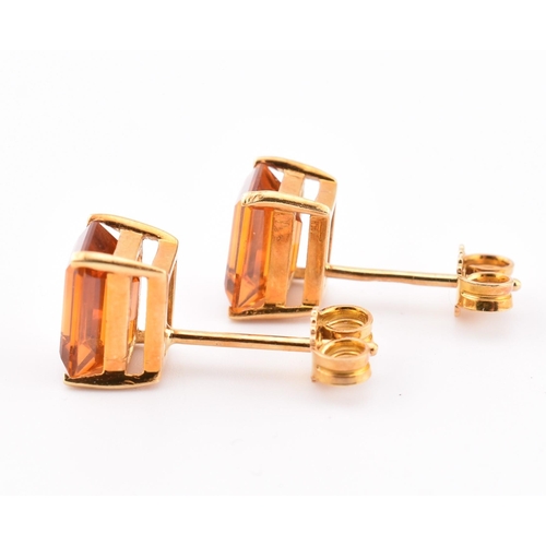 92 - An 18ct gold and citrine pendant and earring suite. The pendant having a claw mounted emerald cut ci... 