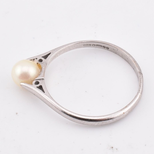 99 - A hallmarked 18ct gold and pearl ring. The 18ct white gold ring set with a single round pearl to che... 