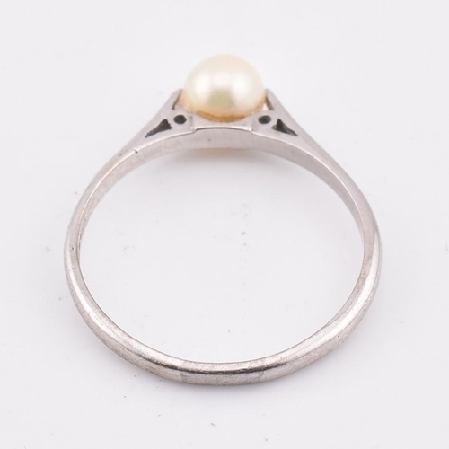 99 - A hallmarked 18ct gold and pearl ring. The 18ct white gold ring set with a single round pearl to che... 