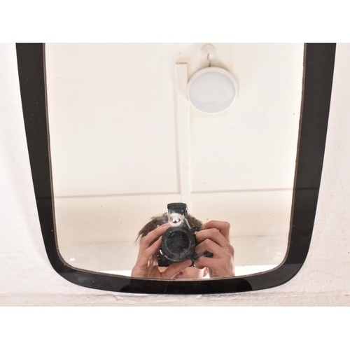 17 - A vintage 20th century Art Deco black glass framed hanging mirror. The mirror having a shaped mirror... 