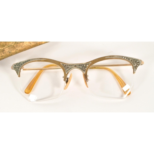 209 - Goldray - A mid 20th century pair of cat eye reading glasses. Having a gilt frame and arms, frameles... 