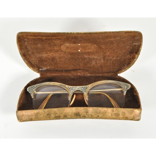 209 - Goldray - A mid 20th century pair of cat eye reading glasses. Having a gilt frame and arms, frameles... 