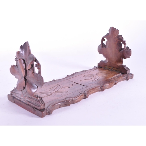 268 - A late 19th century black forest German adjustable book slide. With carved leaves to ends, adjustabl... 