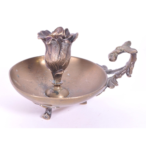 294 - A 19th century Art Nouveau brass candle holder / chamberstick. Foliate carry handle with bowl wax ru... 