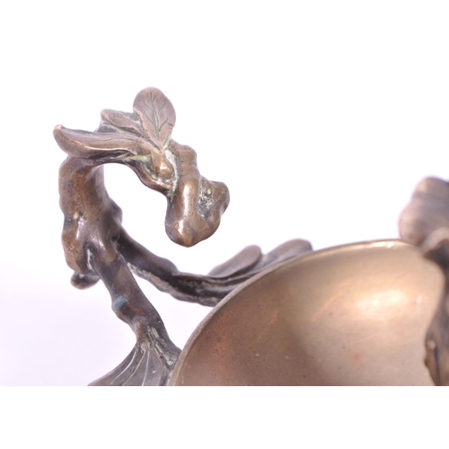 294 - A 19th century Art Nouveau brass candle holder / chamberstick. Foliate carry handle with bowl wax ru... 