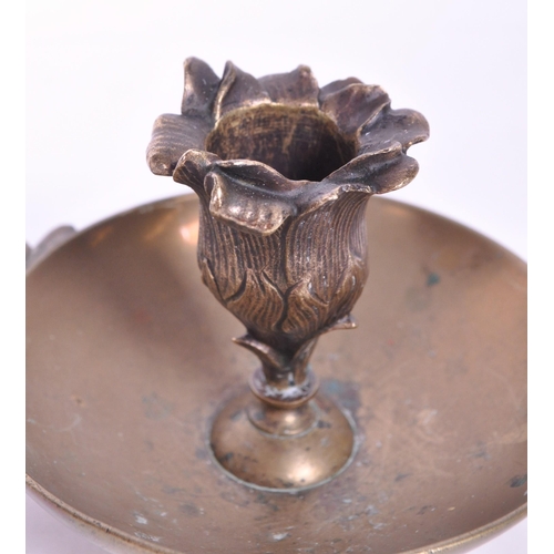 294 - A 19th century Art Nouveau brass candle holder / chamberstick. Foliate carry handle with bowl wax ru... 