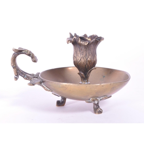 294 - A 19th century Art Nouveau brass candle holder / chamberstick. Foliate carry handle with bowl wax ru... 