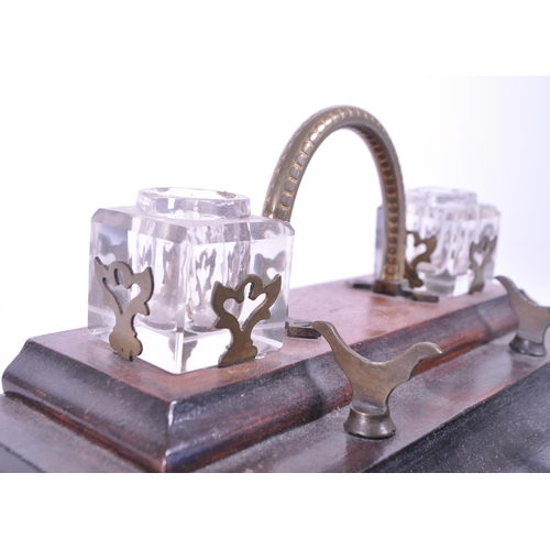 299 - An early 20th mahogany office desk tidy / ink well. With brass carry handle, two cut glass ink wells... 