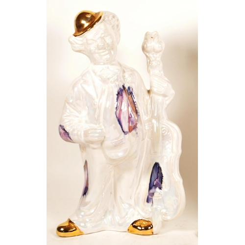 171 - Two large late 20th century ceramic white and gilt clown figures. Both depicted holding a cello, one... 