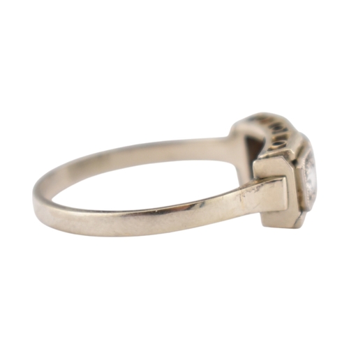 61 - An Art Deco 14ct white gold three stone diamond ring. The ring set with three diamonds within a face... 