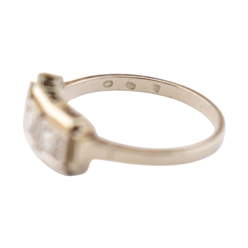 61 - An Art Deco 14ct white gold three stone diamond ring. The ring set with three diamonds within a face... 