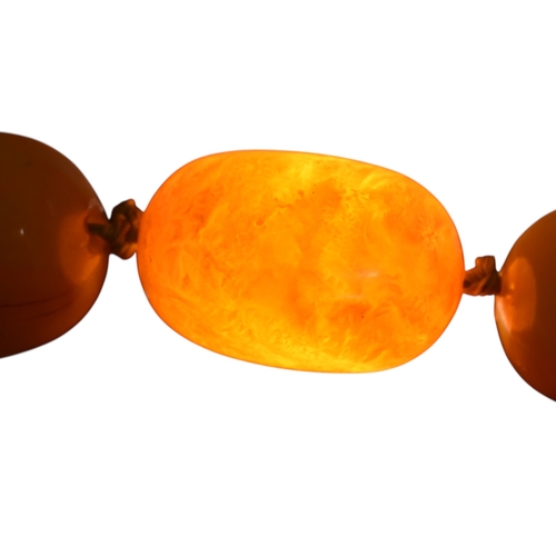 62 - A vintage egg yolk amber bead necklace and earrings. The necklace with large knotted amber beads. Th... 
