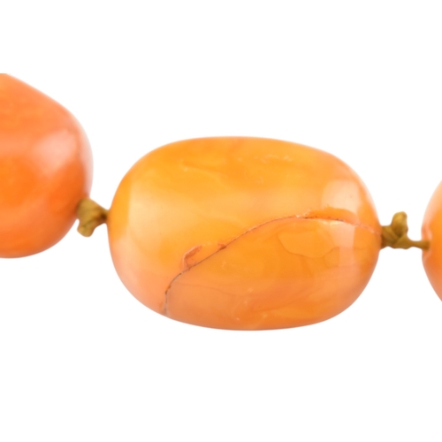 62 - A vintage egg yolk amber bead necklace and earrings. The necklace with large knotted amber beads. Th... 