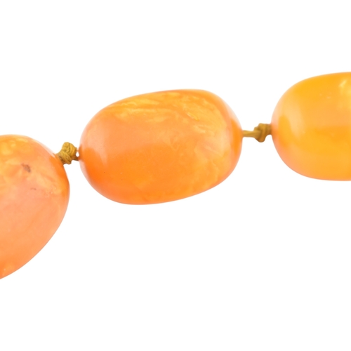62 - A vintage egg yolk amber bead necklace and earrings. The necklace with large knotted amber beads. Th... 