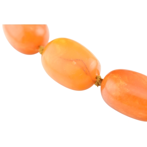 62 - A vintage egg yolk amber bead necklace and earrings. The necklace with large knotted amber beads. Th... 