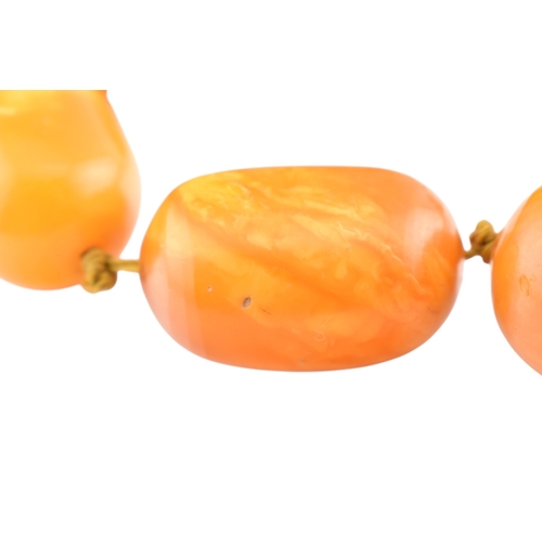 62 - A vintage egg yolk amber bead necklace and earrings. The necklace with large knotted amber beads. Th... 