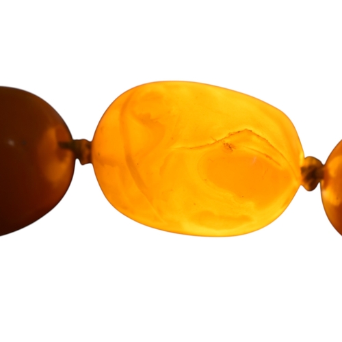 62 - A vintage egg yolk amber bead necklace and earrings. The necklace with large knotted amber beads. Th... 
