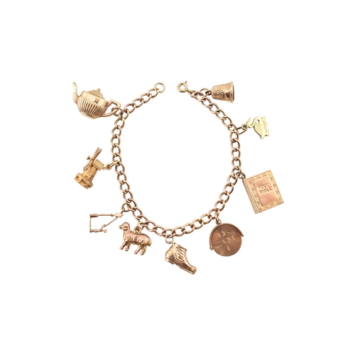 99 - A 9ct gold charm bracelet. The bracelet strung with multiple charms to include a hallmarked bell, a ... 