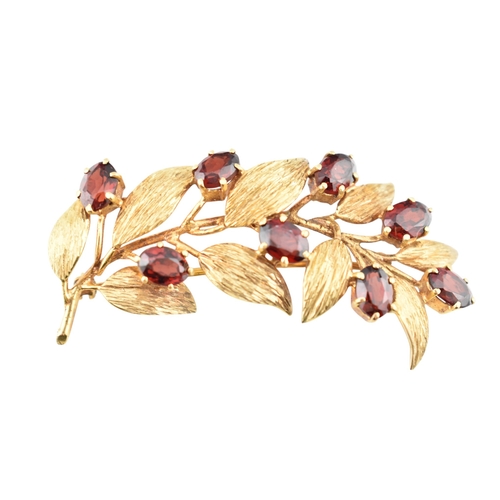 107 - A hallmarked 9ct gold and garnet spray brooch pin. The brooch is set with oval cut garnets within te... 