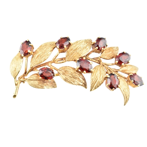 107 - A hallmarked 9ct gold and garnet spray brooch pin. The brooch is set with oval cut garnets within te... 