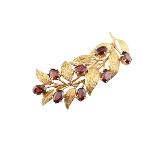 107 - A hallmarked 9ct gold and garnet spray brooch pin. The brooch is set with oval cut garnets within te... 