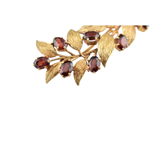 107 - A hallmarked 9ct gold and garnet spray brooch pin. The brooch is set with oval cut garnets within te... 