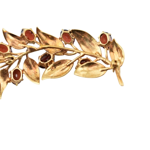 107 - A hallmarked 9ct gold and garnet spray brooch pin. The brooch is set with oval cut garnets within te... 
