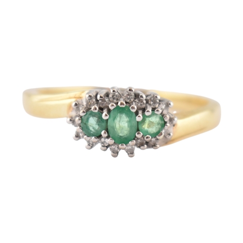 188 - A hallmarked 18ct gold emerald and diamond three stone ring. The ring set with three emeralds framed... 
