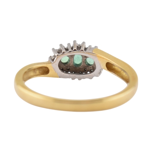 188 - A hallmarked 18ct gold emerald and diamond three stone ring. The ring set with three emeralds framed... 