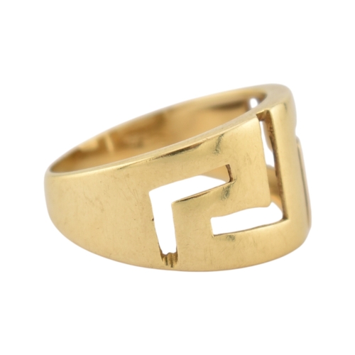 216 - An 18ct gold band ring. The ring with pierced Greek key decoration. Stamped 750. Weight 5.9g. Size R... 