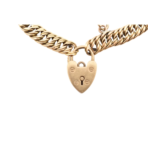 335 - A 15ct gold fancy link bracelet adorned with a 9ct gold hallmarked heart padlock. Stamped 15ct to br... 
