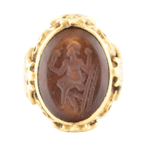 355 - A gold intaglio ring. The ring with a central intaglio depicting a warrior set within an ornate moun... 