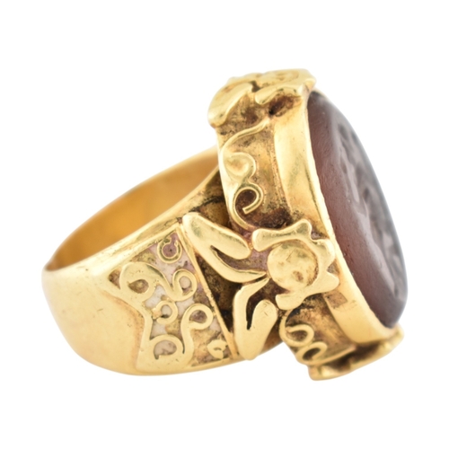 355 - A gold intaglio ring. The ring with a central intaglio depicting a warrior set within an ornate moun... 