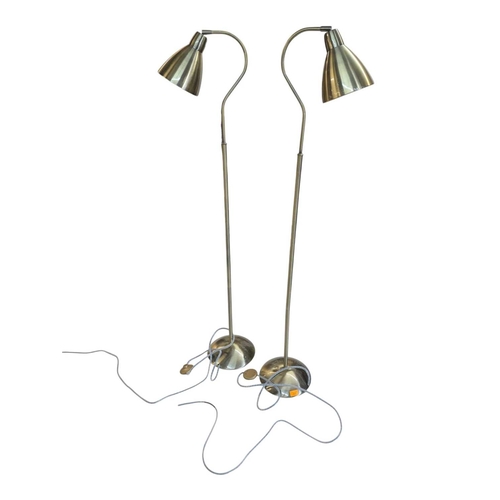 622 - Two contemporary floor standing metal lamps. In a gilt colourway with curved arm terminating in coni... 