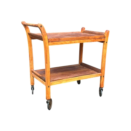 627 - British Modern Design - A mid century teak wood butlers trolley. Raised on squared legs with twin ti... 