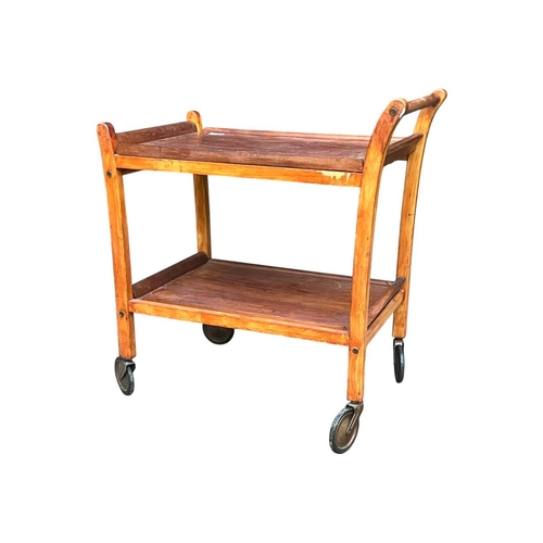 627 - British Modern Design - A mid century teak wood butlers trolley. Raised on squared legs with twin ti... 
