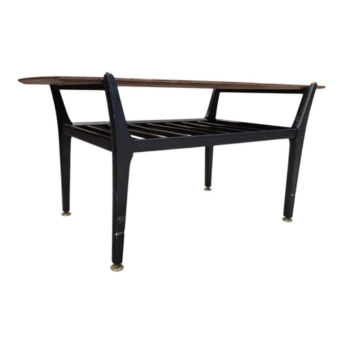 648 - A mid-century British design tola wood coffee table with ebonised legs and slatted magazine rack bel... 