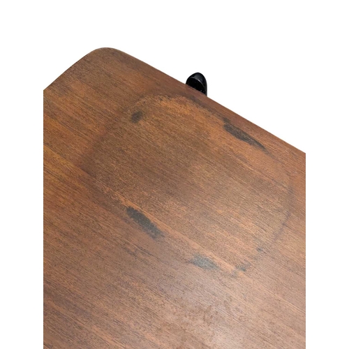 648 - A mid-century British design tola wood coffee table with ebonised legs and slatted magazine rack bel... 