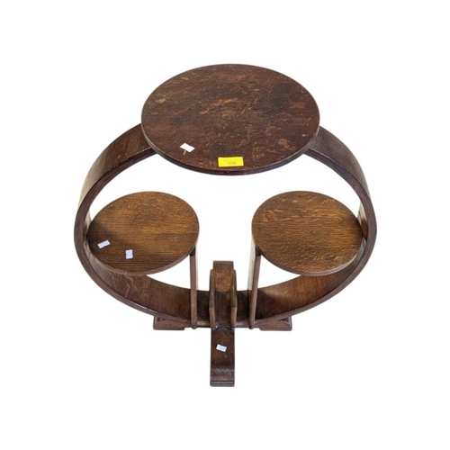 656 - An Art Deco oak display stand / magazine rack. Having a circular top with curved supports, with smal... 