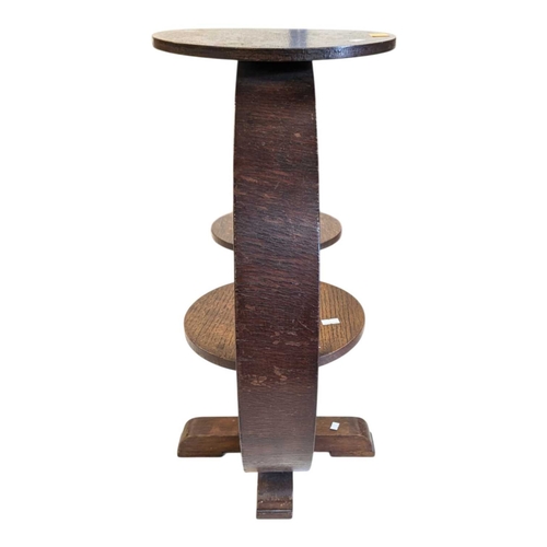 656 - An Art Deco oak display stand / magazine rack. Having a circular top with curved supports, with smal... 