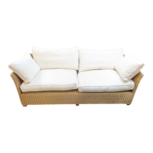 666 - A large contemporary rattan whicker weave conservatory sofa with large squab white cushions. Measure... 