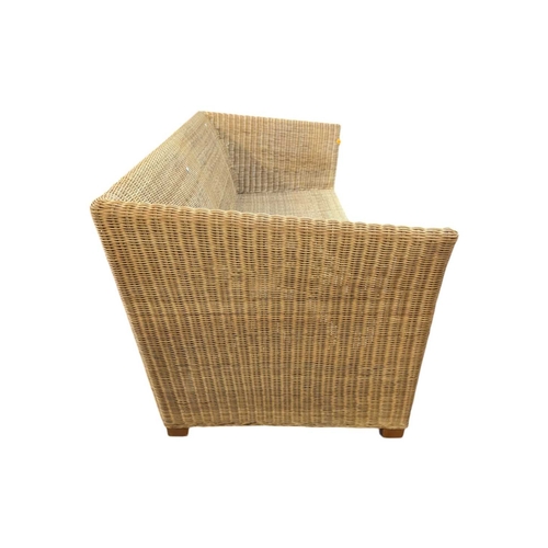 666 - A large contemporary rattan whicker weave conservatory sofa with large squab white cushions. Measure... 