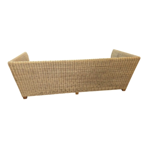 666 - A large contemporary rattan whicker weave conservatory sofa with large squab white cushions. Measure... 