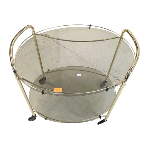 674 - A contemporary brass and smoked glass drinks / hostess trolley in the Art Deco style. Having gilt tu... 